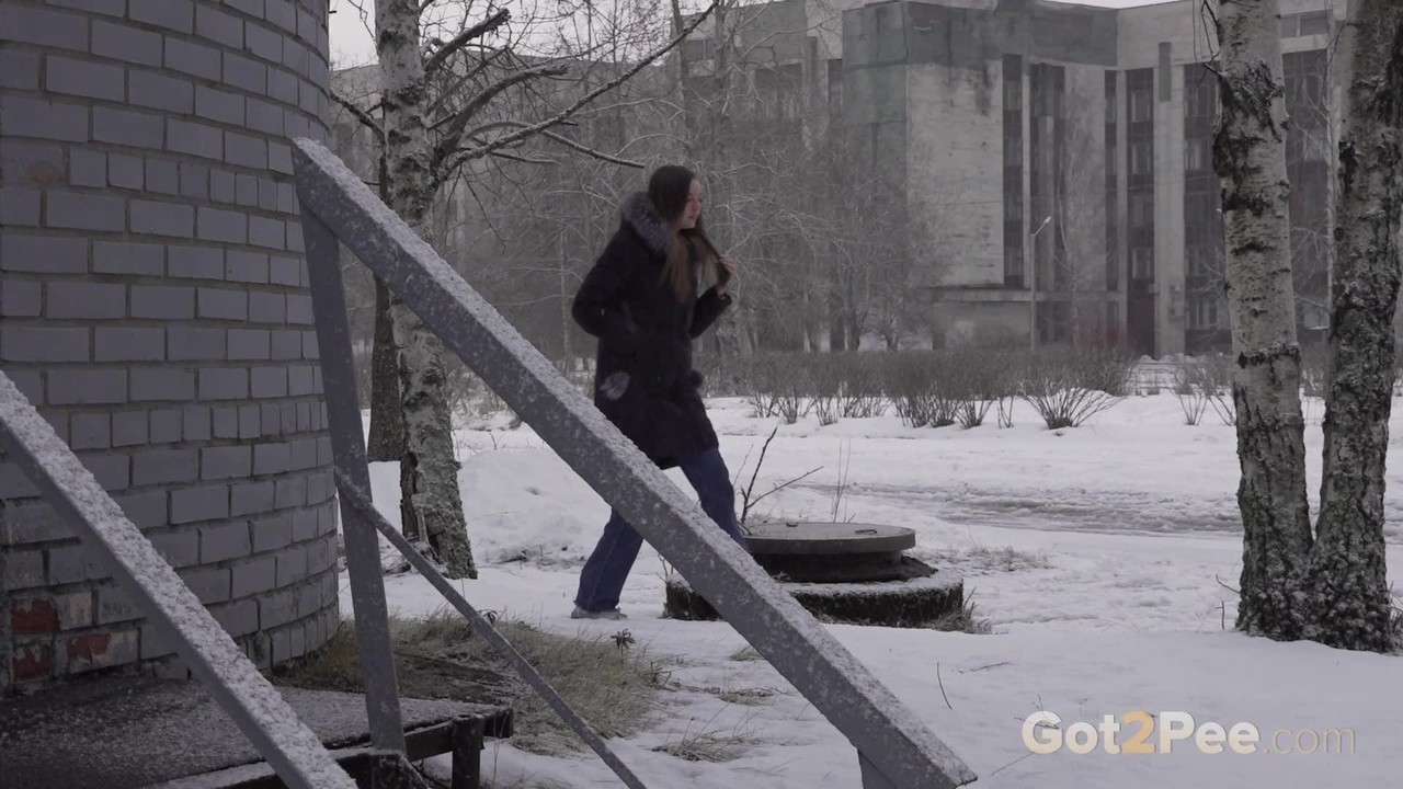White girl pulls down her jeans to pee in the snow behind a building  